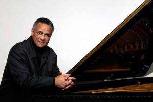 Pianist Andre Watts poses in front of a piano.